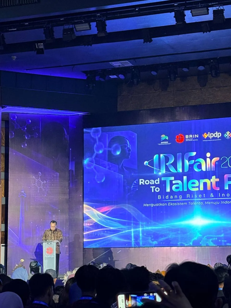 Pembicara menyampaikan paparan dari podium di hadapan audiens